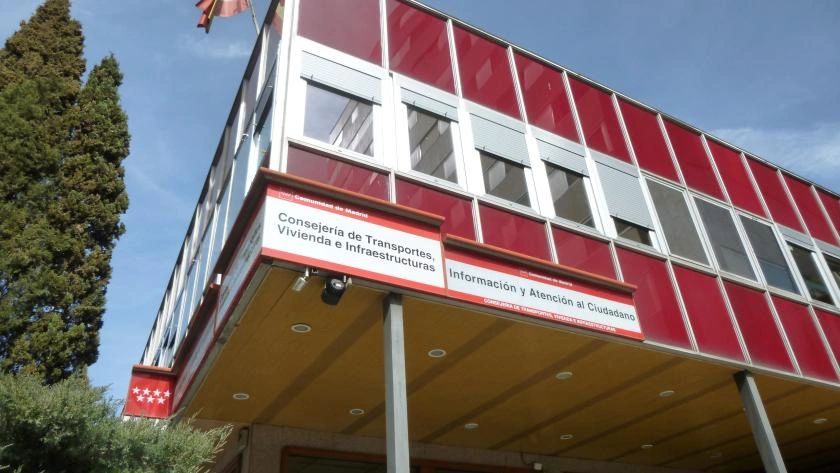 Fachada de la sede de la Consejería de Transportes, Vivienda e Infraestructuras de la Comunidad de Madrid, edificio de cristales rojos con el cartel de Información y Atención al Ciudadano